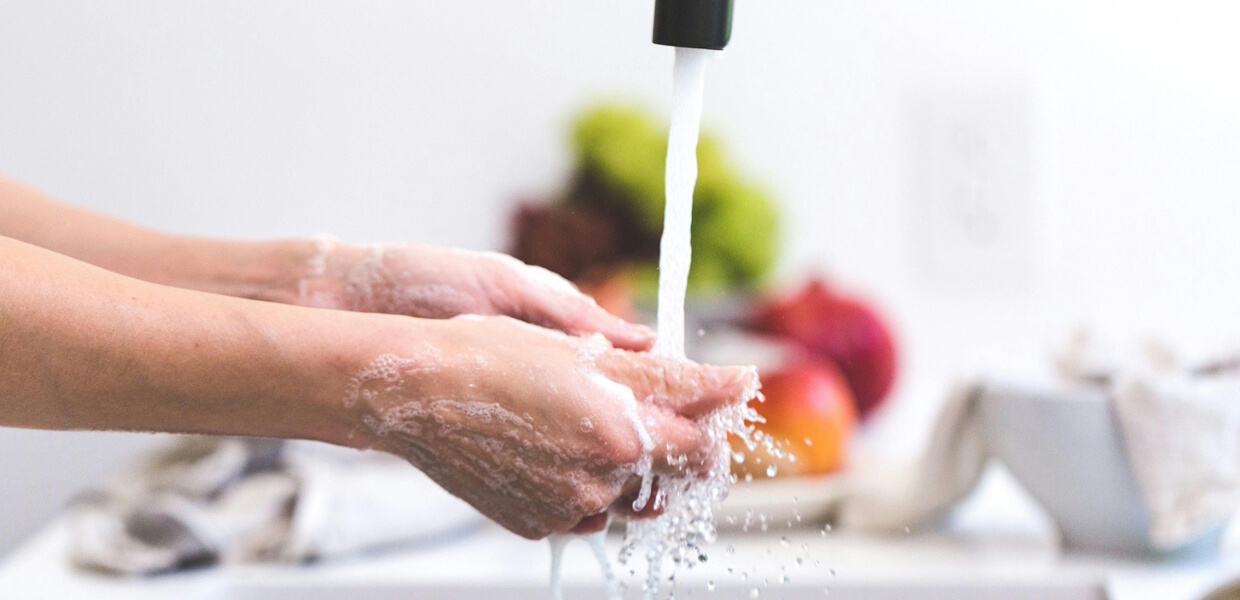 a close-up shot of someone washing their hands in a bright kitchen
