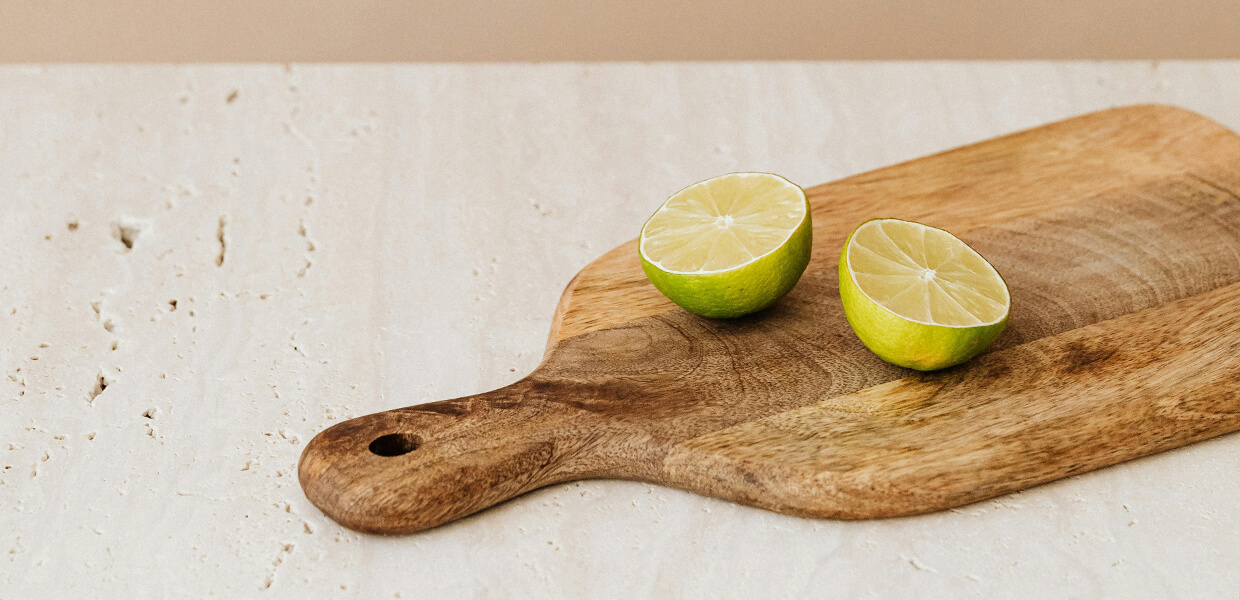 a wooden chopping board sitting on a marble worktop with a lemon sliced in half