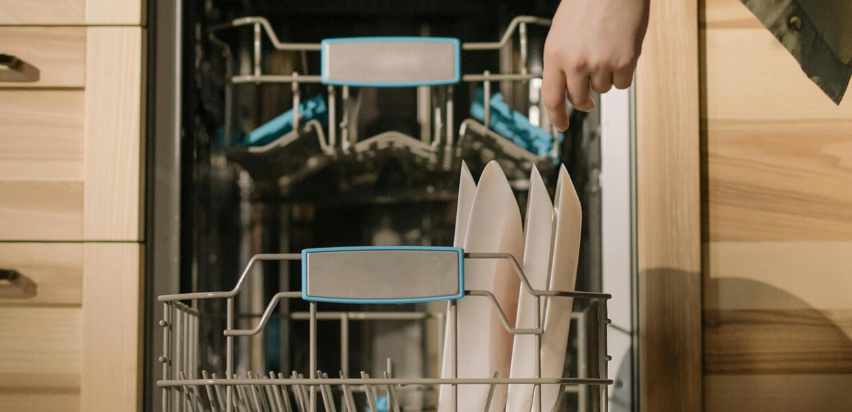 a teenager stacking plates into an integrated dishwasher